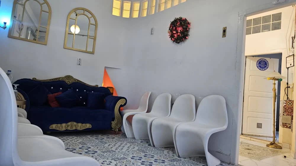 Salle d’attente du centre dentaire Bahia Smile à Oran, avec canapé bleu sculpté et fauteuils blancs